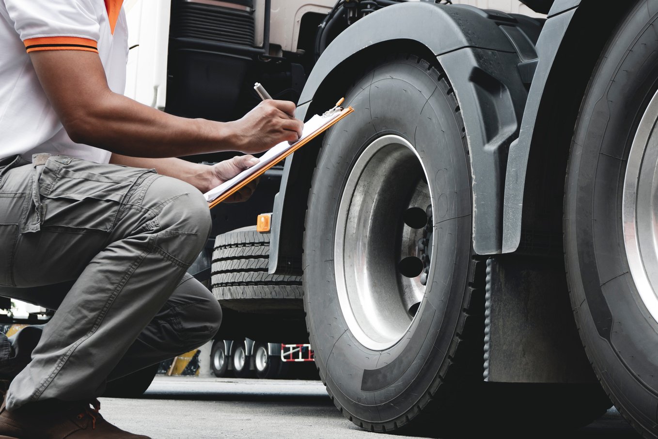 truck inspection and safety, truck driver hand holding clipboard with safety check a truck tires.