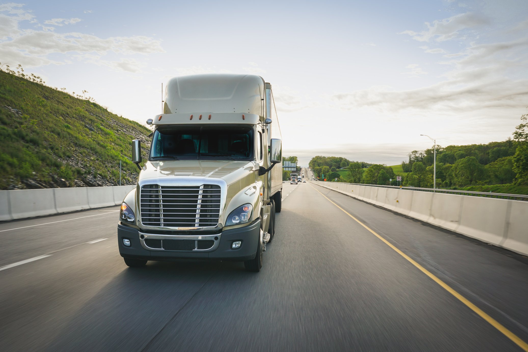 18 wheeler semi-truck trucking on highway at sunrise